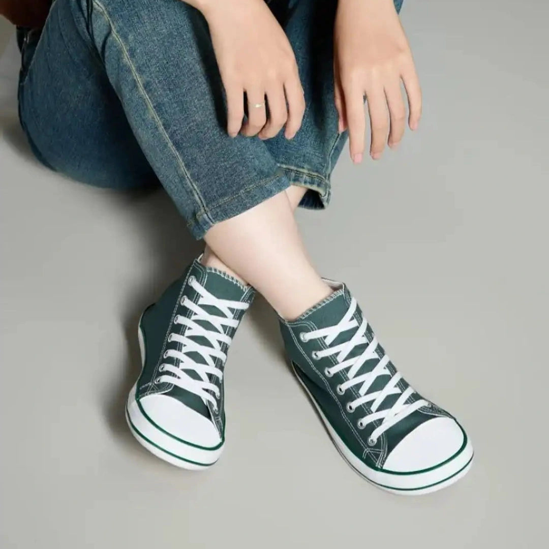Mujer sentada usando zapatillas barefoot mujer verdes de lona con jeans.