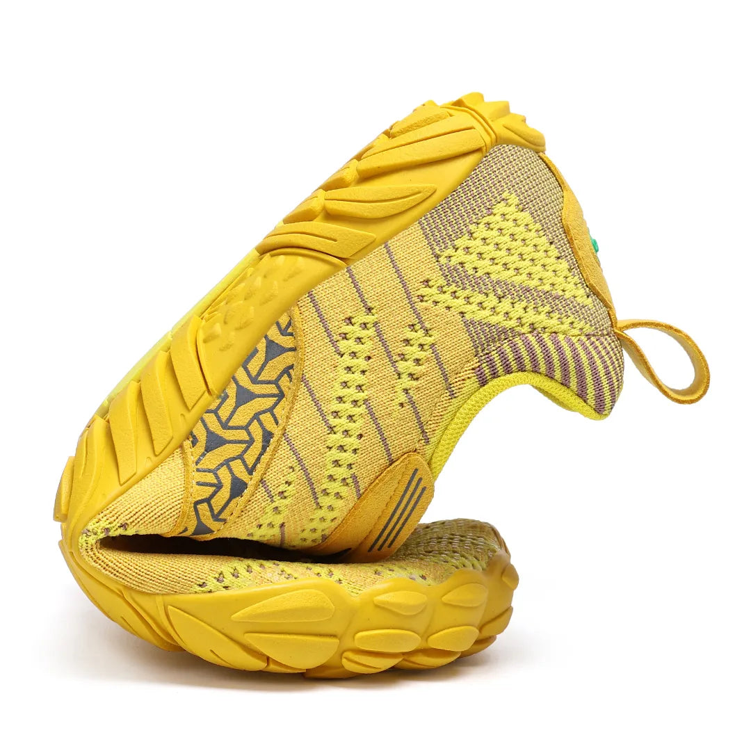 Zapatilla barefoot amarilla doblada demostrando suela totalmente flexible.