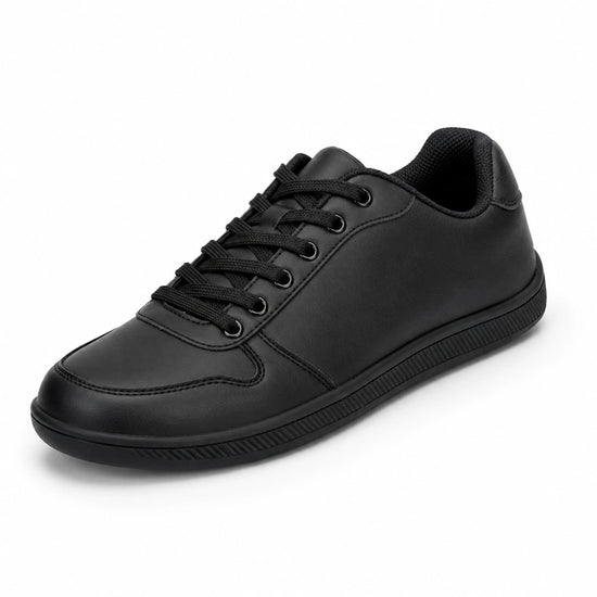 Zapatilla minimalista negra de piel sintética, estilo urbano y oficina.