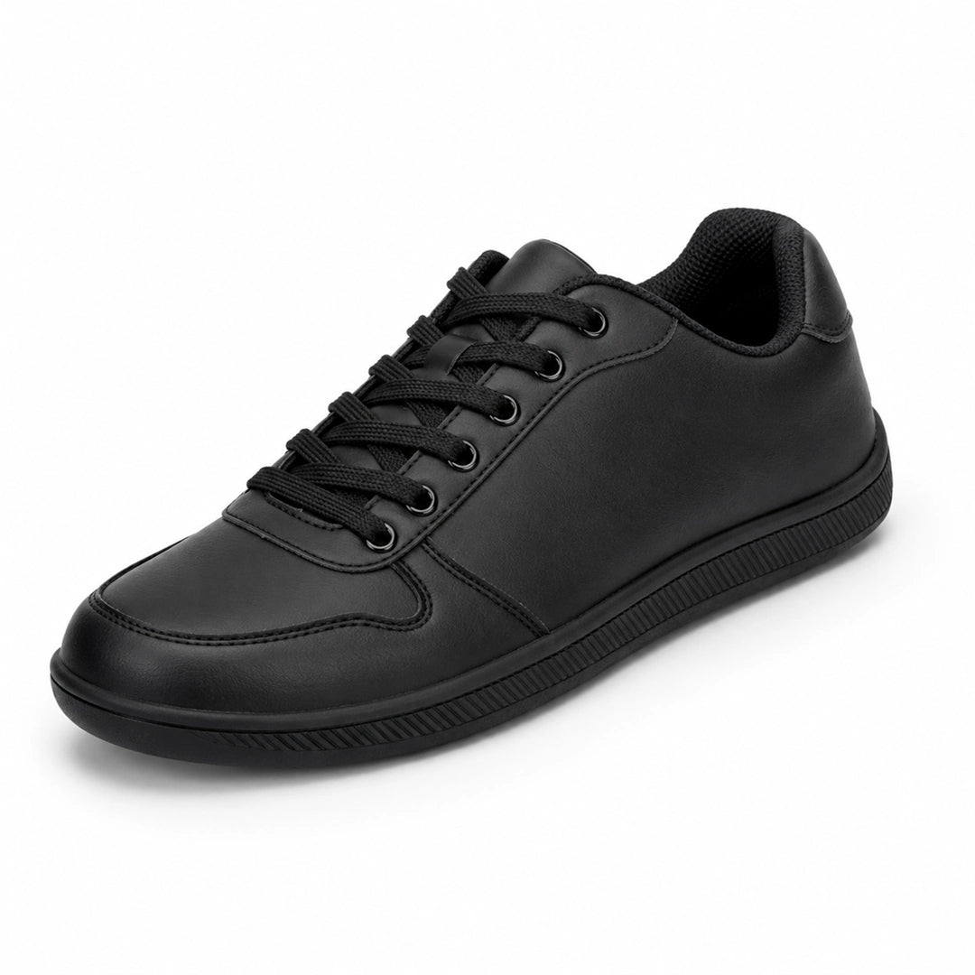 Zapatilla minimalista negra de piel sintética, estilo urbano y oficina.
